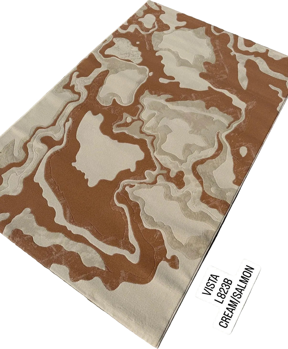 A rectangular area rug with an abstract, organic wavy pattern in brown and cream, displayed diagonally on a gray paved surface. Two small white stickers on the bottom right read 'VISTA L828B' and 'CREAM/SALMON'.
