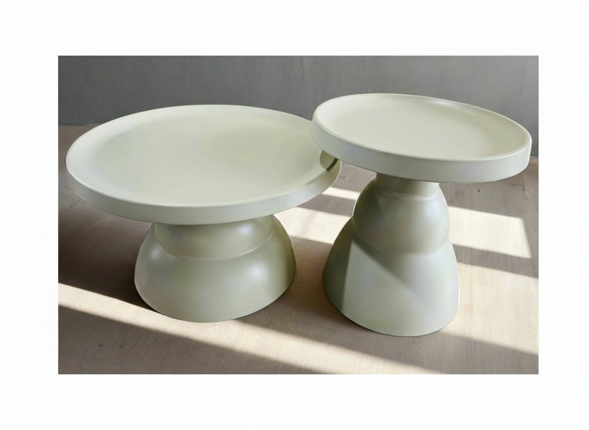 Two light green plastic ceramic looking pedestal tables on a neutral background
