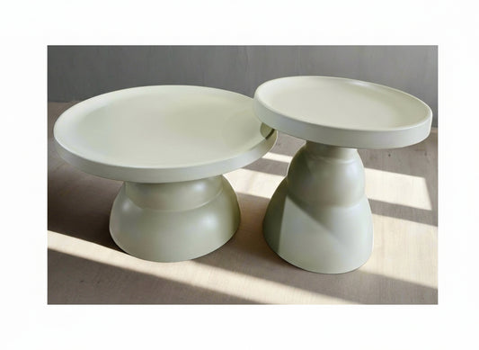 Two light green plastic ceramic looking pedestal tables on a neutral background