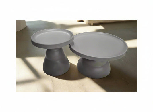 Two gray faux ceramic cake stands on a light wooden surface.