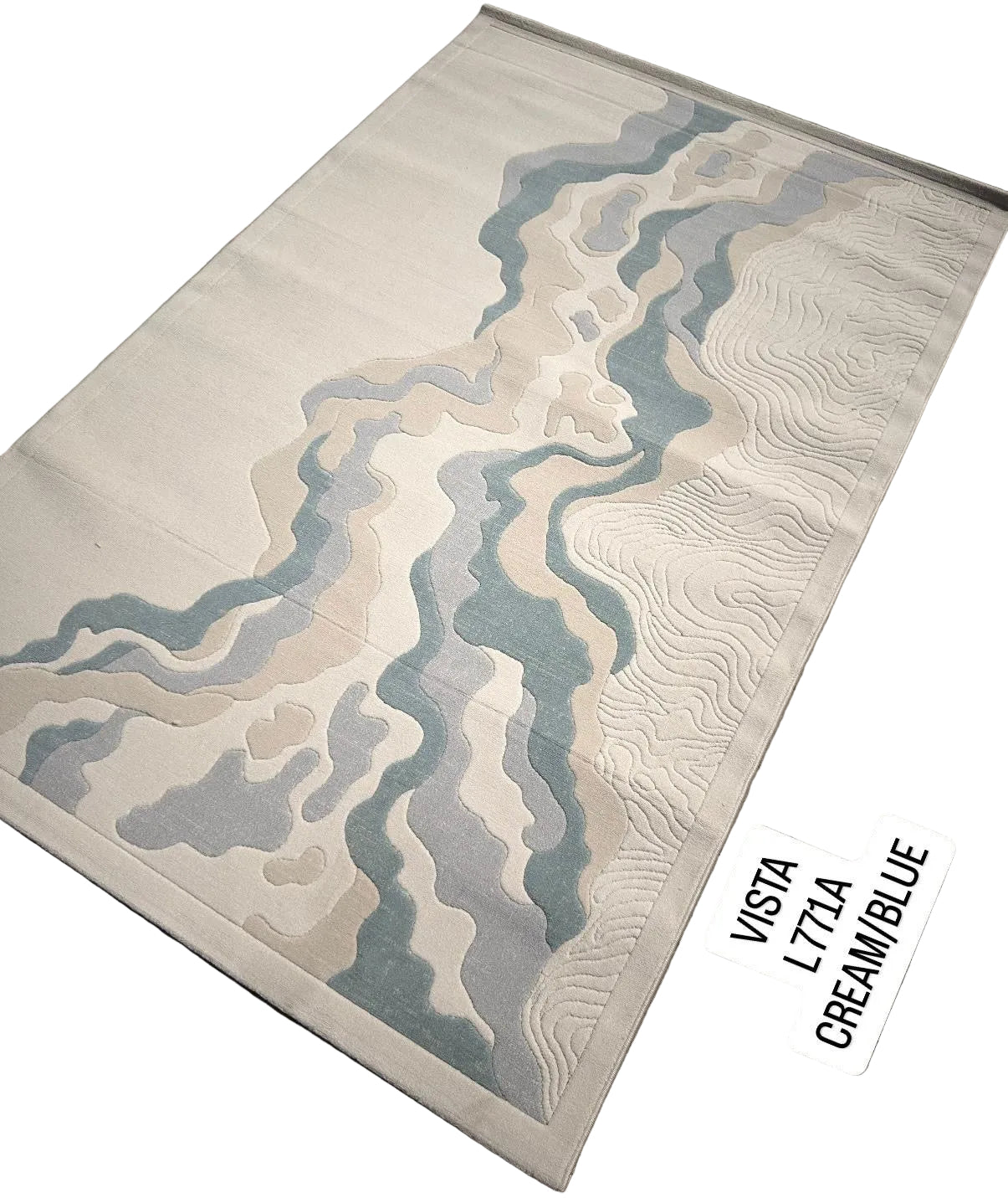 A rectangular area rug with an abstract topographic river pattern in shades of cream, beige, light blue, and gray, displayed on a gray textured floor with a white label overlay.